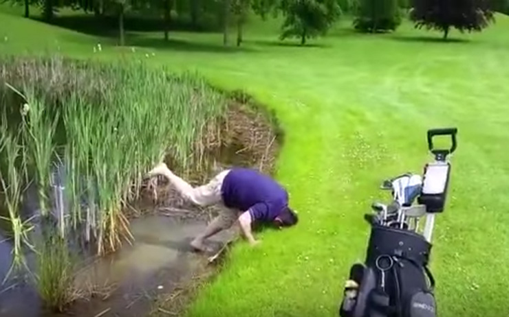 Watch a man try to hit ball out of a lake, but lose his golf club instead
