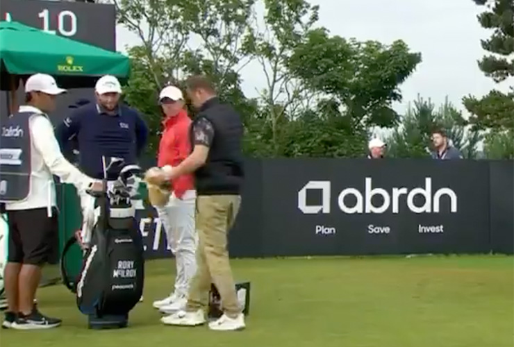 A stunned Rory McIlroy watches spectator take a club from his bag, pretend to hit tee shot